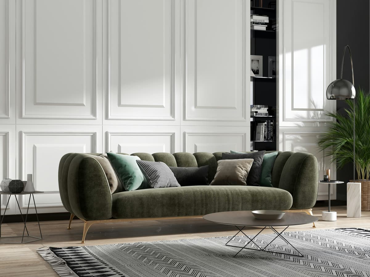 Panelled sitting room painted in soft white with a green velvet sofa, decorated in a Quarndon period home